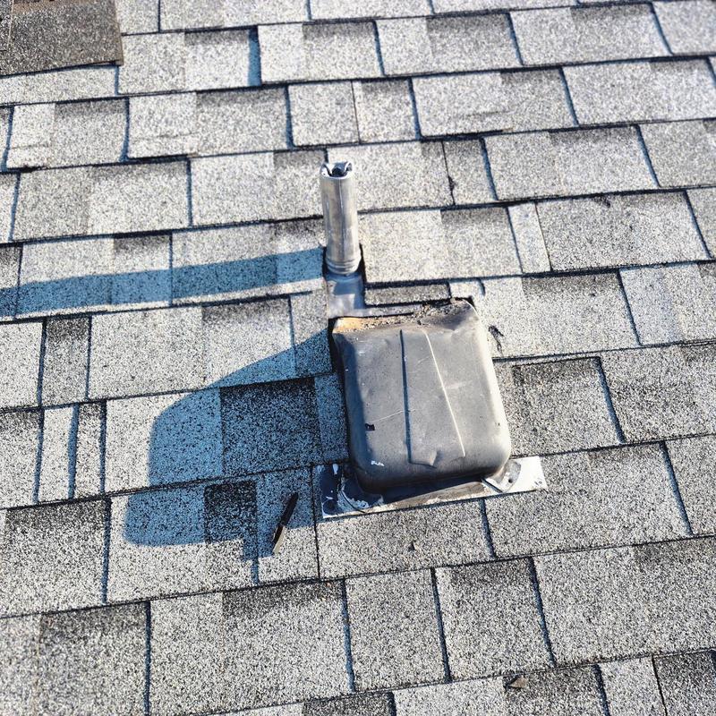Pipe boot on roof with damaged shingles and wear