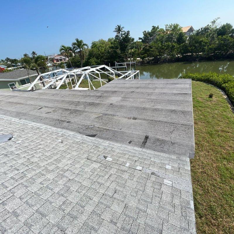 Shingle roof and flat roof damage near waterway
