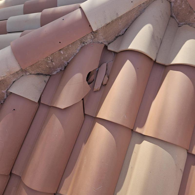 Tile roof with broken and cracked tiles close-up