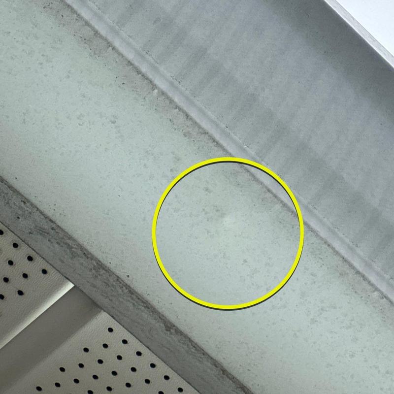 Roof flashing hail damage circled in yellow on metal panel