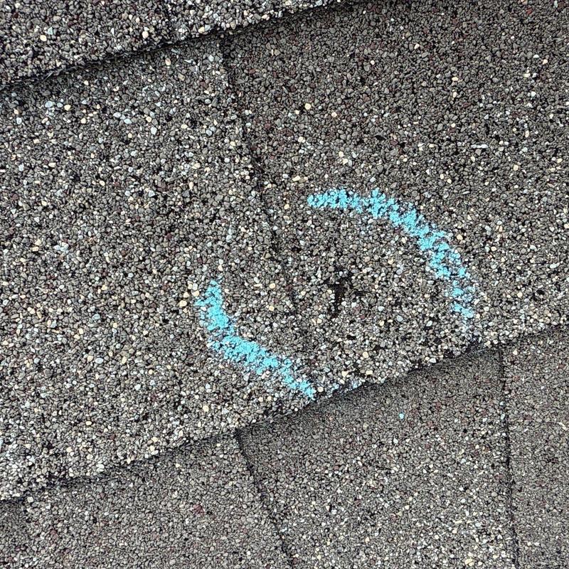 Roof shingles with hail damage marked for repair