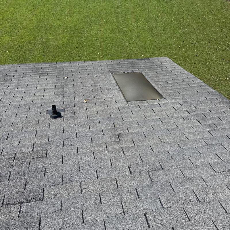 Hail-damaged shingles and flashing on gray roof