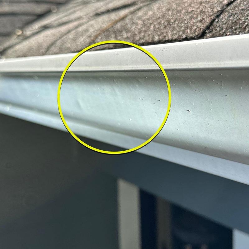Roof gutter with hail damage dents close-up