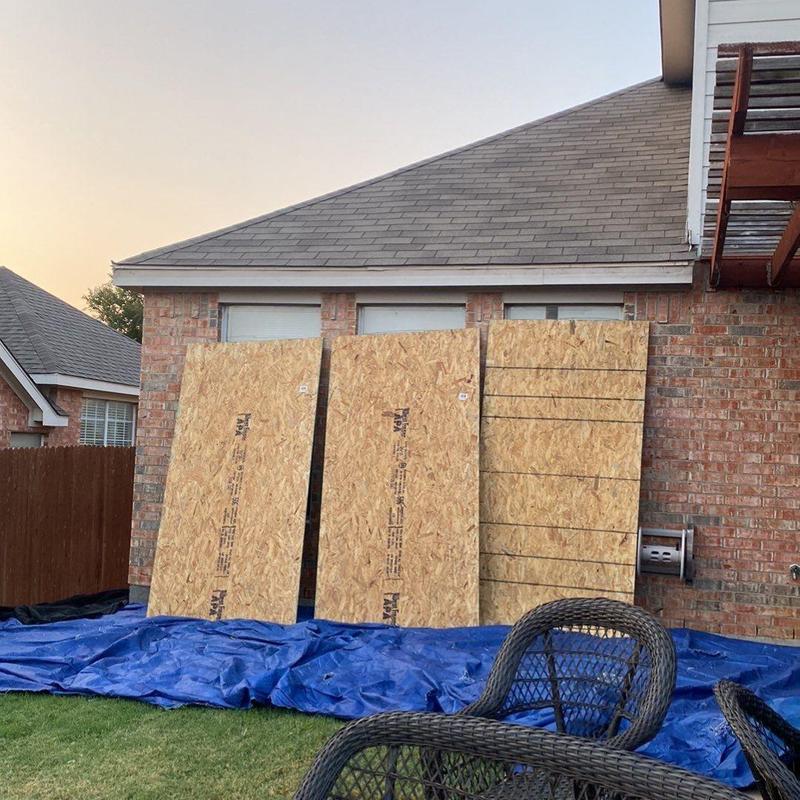 Window protection plywood panels leaning on house after storm repairs