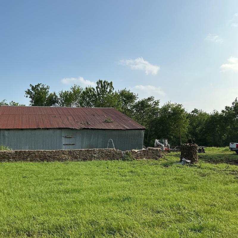 Metal barn with storm damage and cleanup equipment nearby Metal barn with storm damage and cleanup equipment nearby