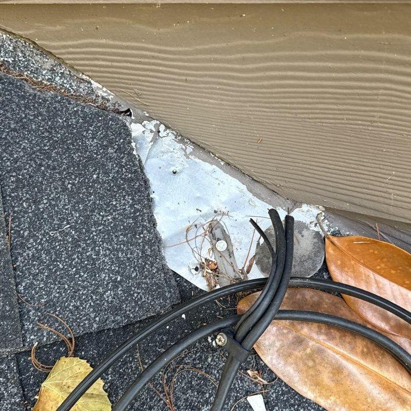 Roof edge flashing with hail-damaged shingles and debris