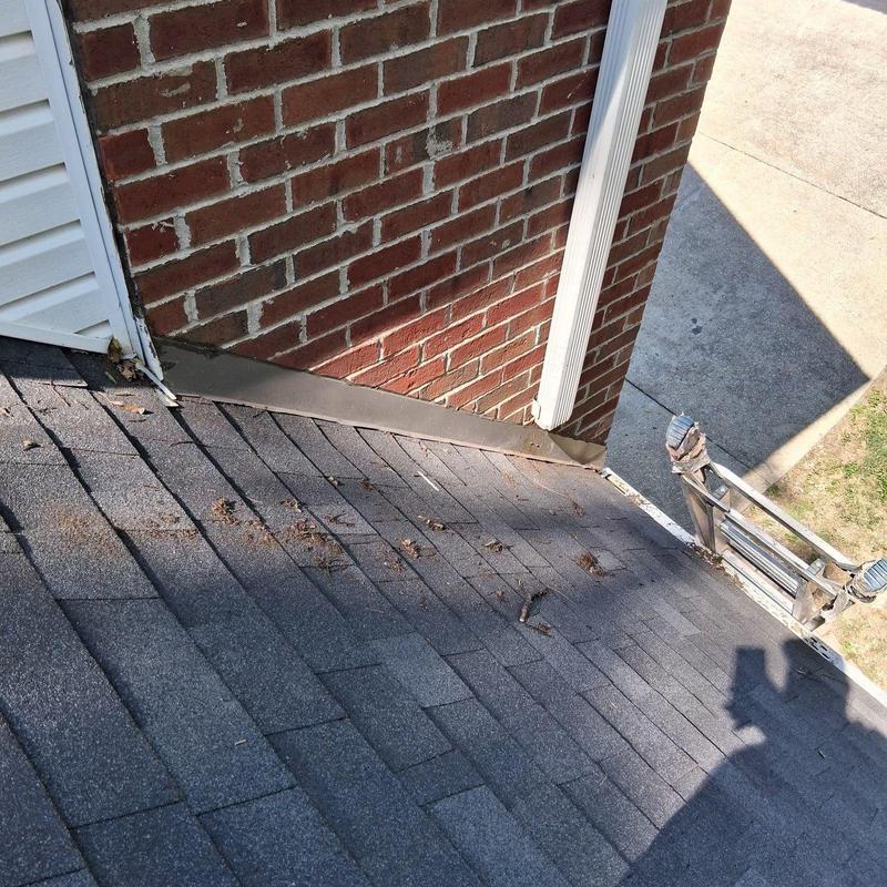 Roof flashing and shingle inspection with ladder nearby