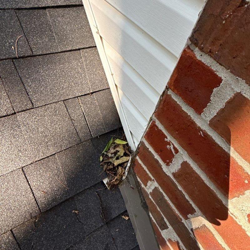 Roof flashing with debris near brick and siding junction