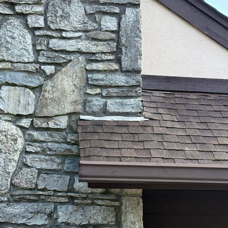 Roof shingles and stone chimney flashing detail