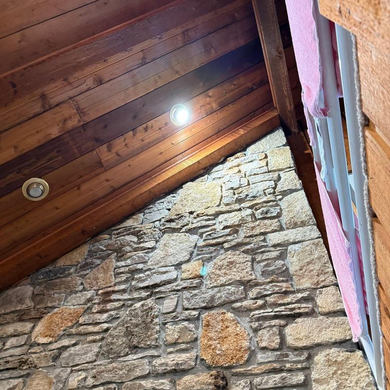 Wood ceiling with recessed lighting and stone wall