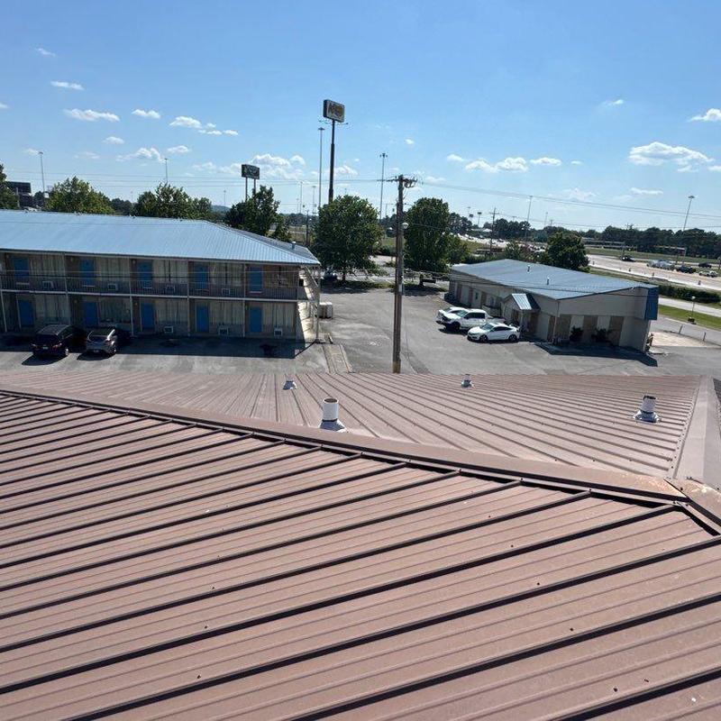 Metal commercial roof with hail damage and ventilation pipes