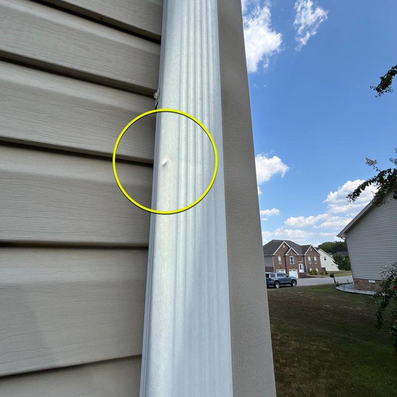 Metal downspout dent with siding and neighborhood view