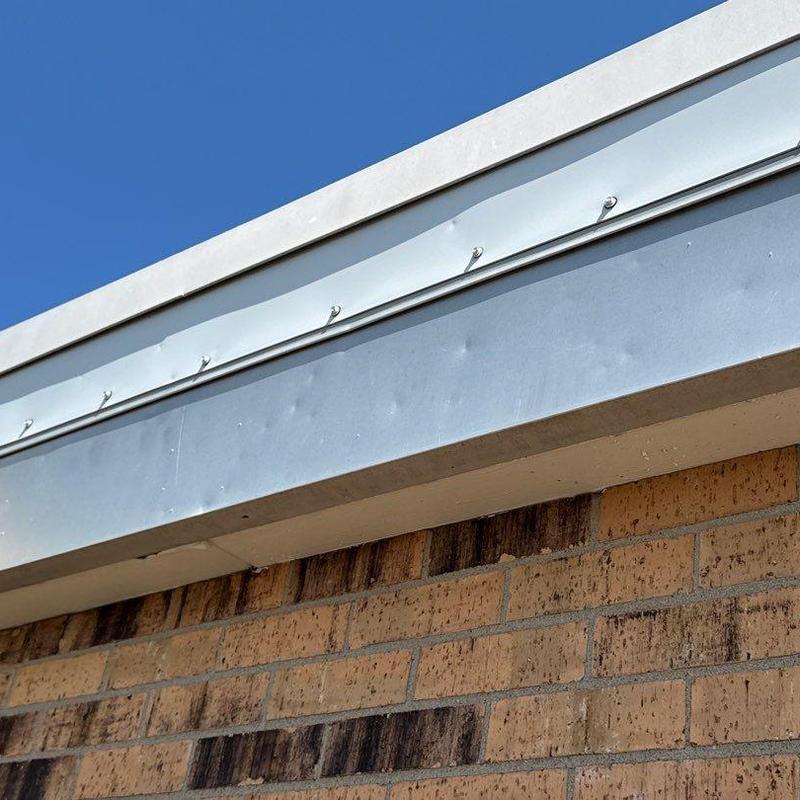 Metal roof edge with visible hail damage dents