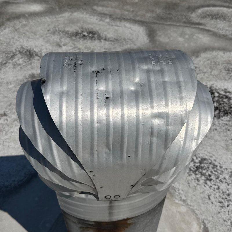 Metal roof vent cap with visible hail dents