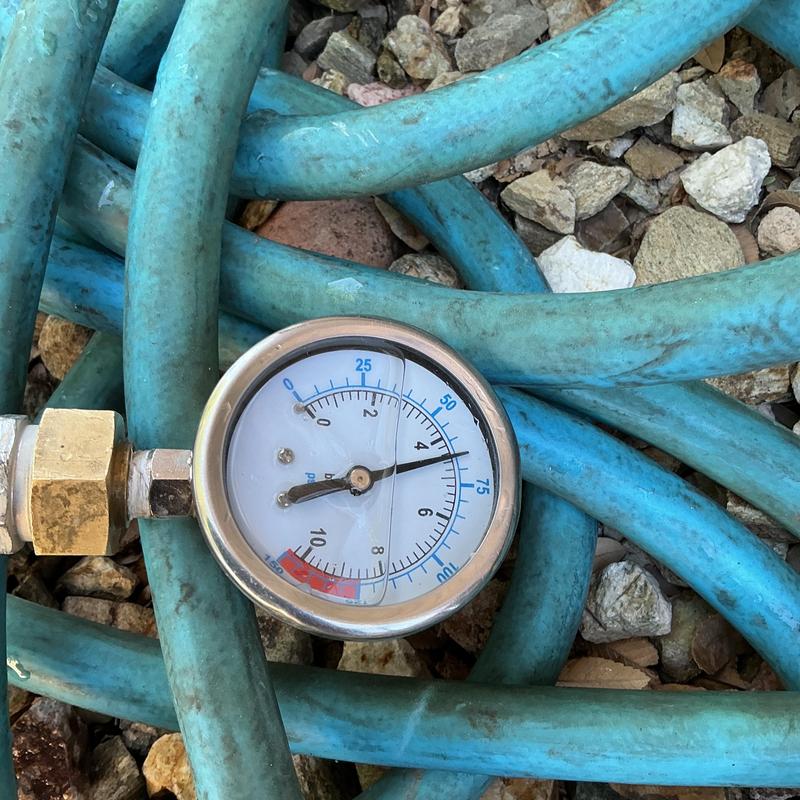 Pressure gauge on blue water hose with gravel background Pressure gauge on blue water hose with gravel background