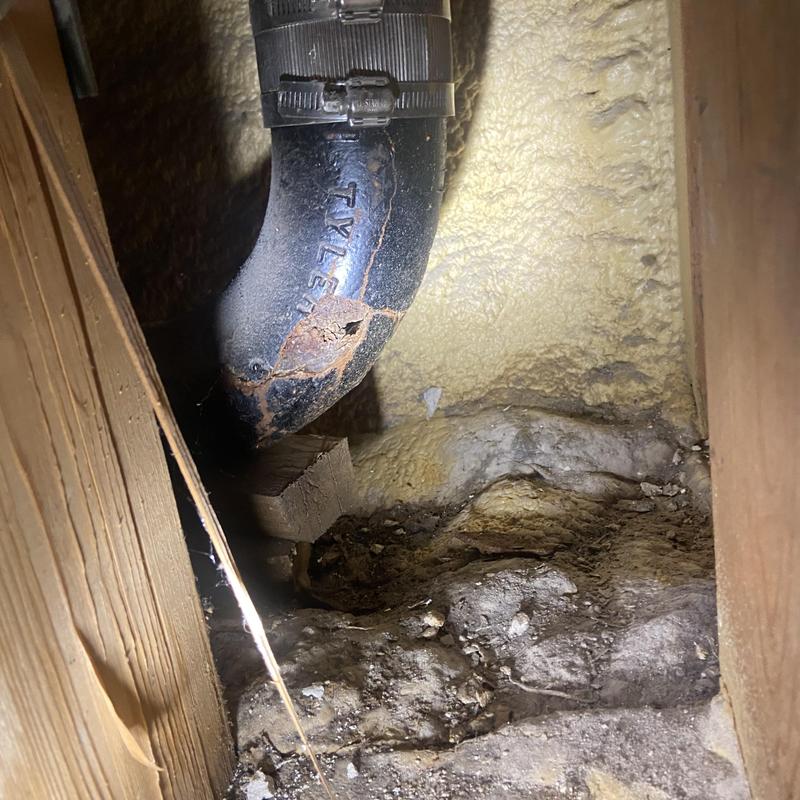 Drain line pipe with corrosion and cracks exposed in wall cavity