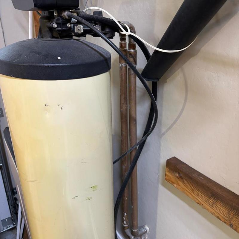 Water softener unit with pipes and hoses in garage