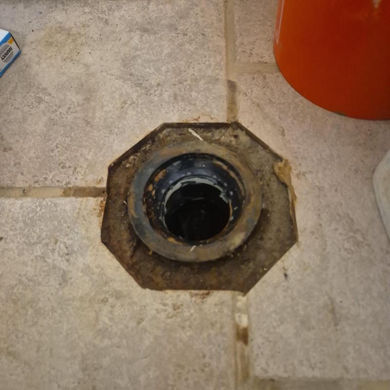 Toilet flange on tiled floor with surrounding damage Toilet flange on tiled floor with surrounding damage