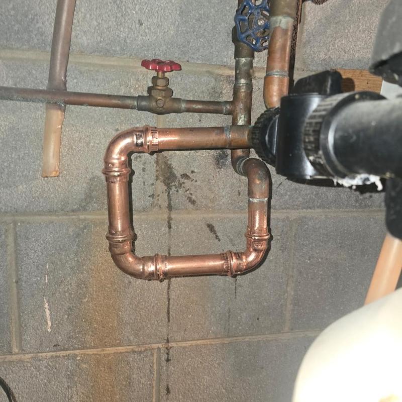 Copper plumbing pipes with valves in basement wall