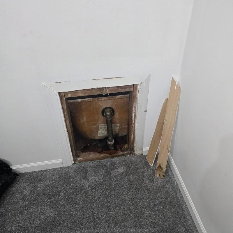 Water heater plumbing access panel removed in carpeted room
