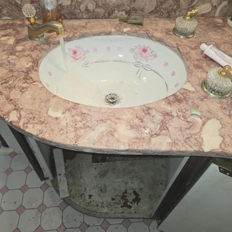 Bathroom sink drain with running faucet and broken countertop