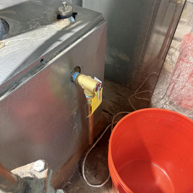 Boiler pressure relief valve and red bucket nearby