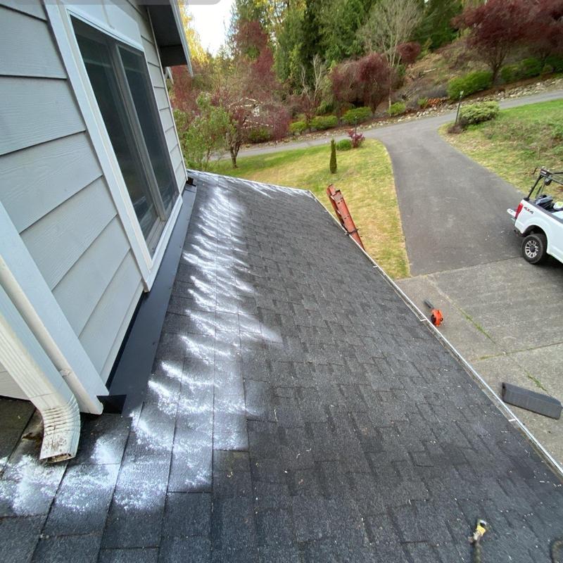 Asphalt roof with moss treatment and cleaning in progress