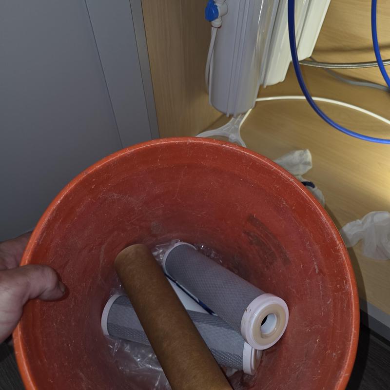 Water filter cartridges in orange bucket under sink