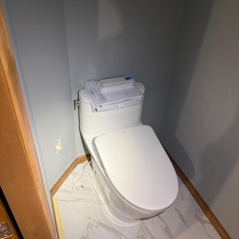 Toilet with closed lid and documents on top in bathroom