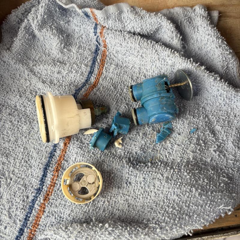 Broken blue shower cartridge parts on towel