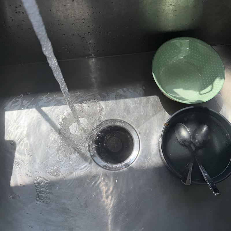Kitchen sink drain with flowing water and dishes