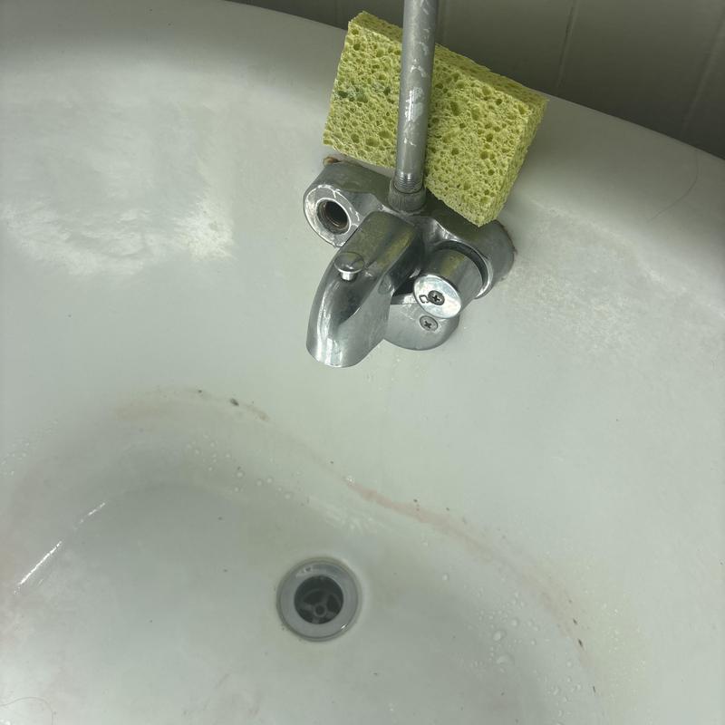 Bathroom faucet with sponge on bathtub edge