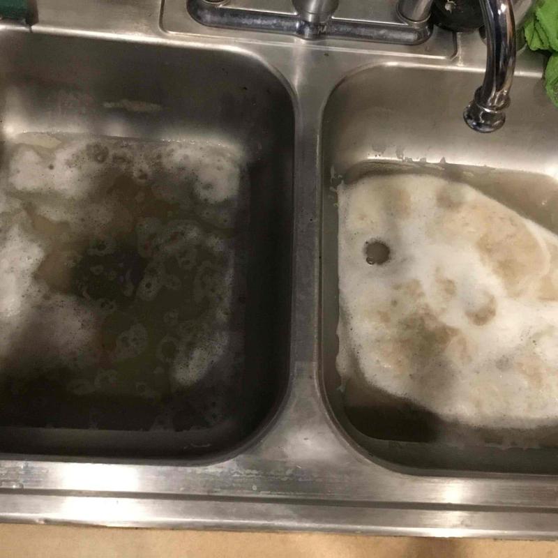 Kitchen sink with clogged, dirty water and foam