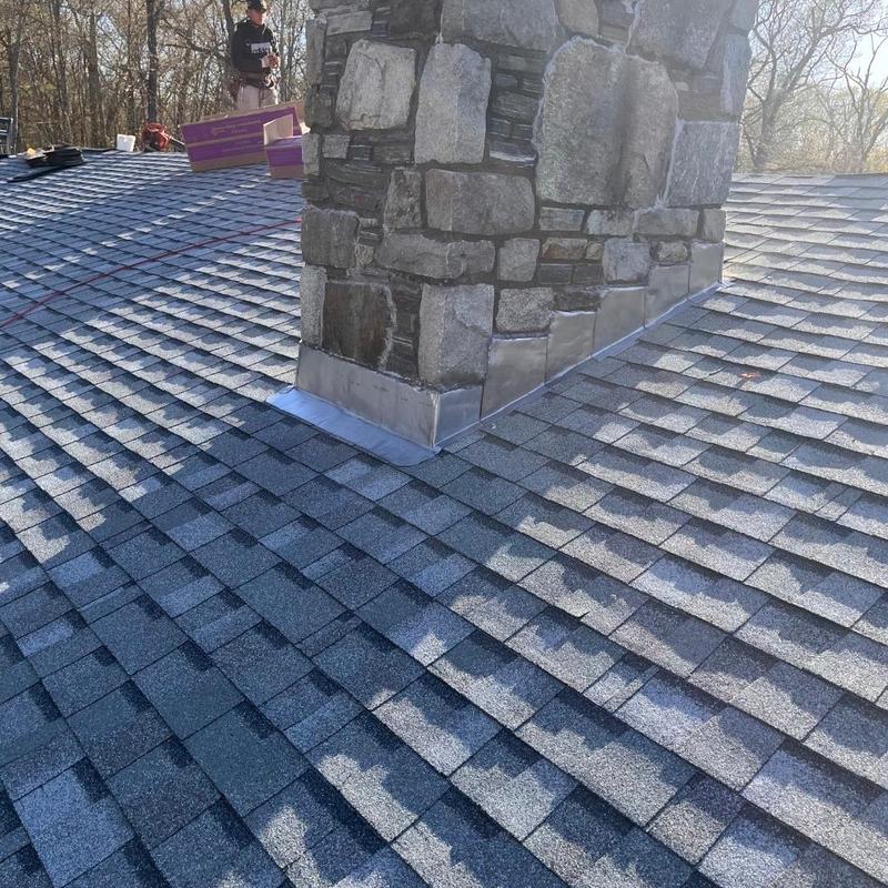 Asphalt shingle roof with stone chimney flashing installation
