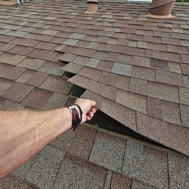 Asphalt shingles with hail damage lifted on roof