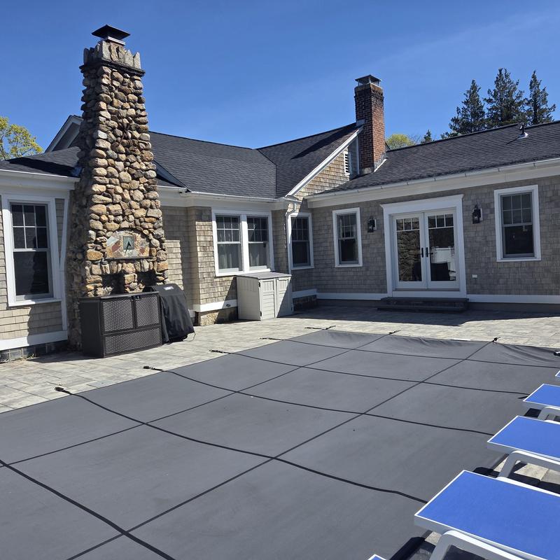 Pool cover installation with stone chimney background