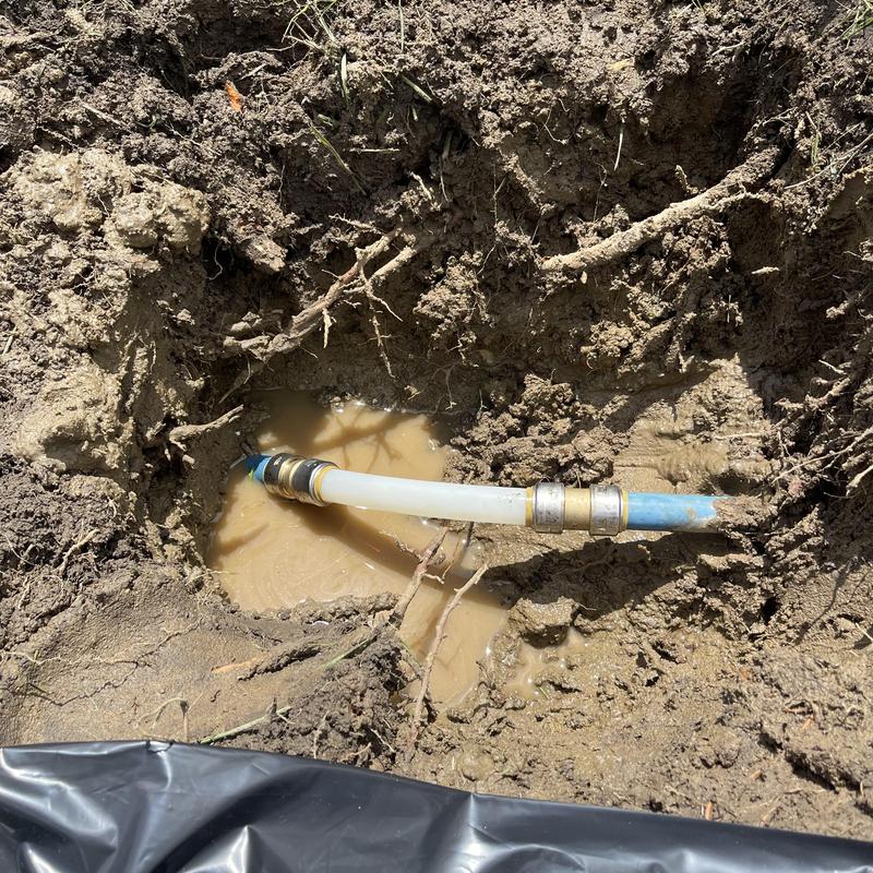 1-inch PEX pipe repair in muddy trench outdoors