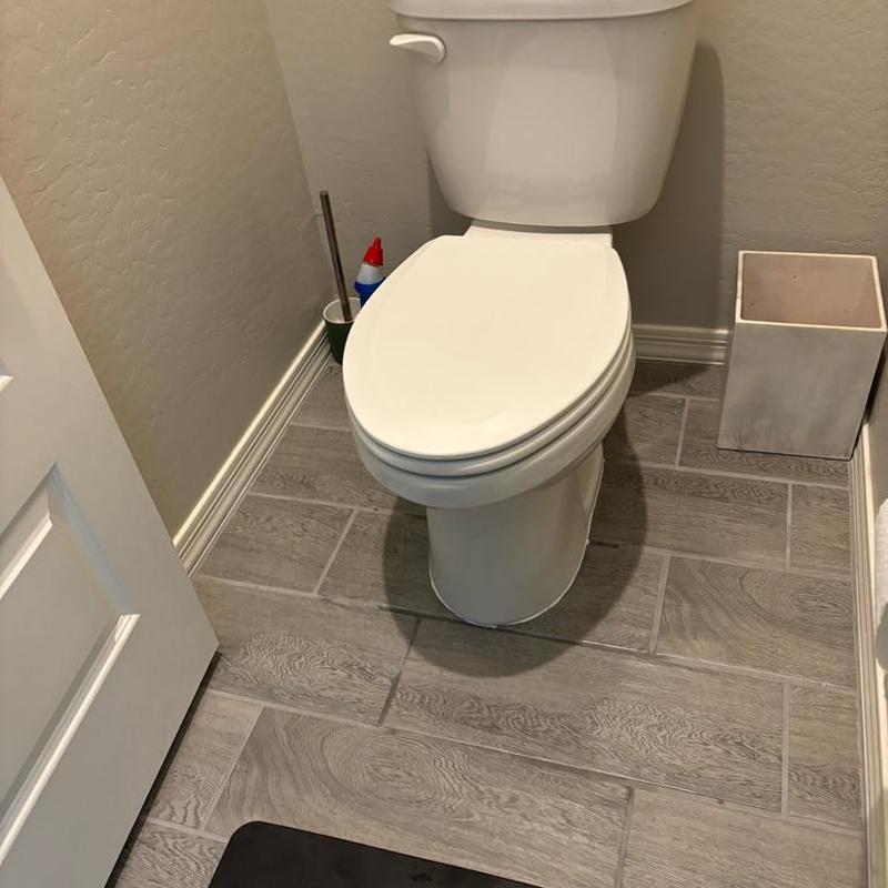 Toilet shimmed and caulked to floor in bathroom