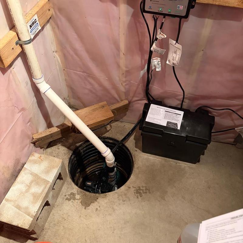 Backup sump pump installation in basement corner