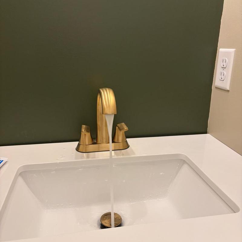 Lav faucet with water running in white sink