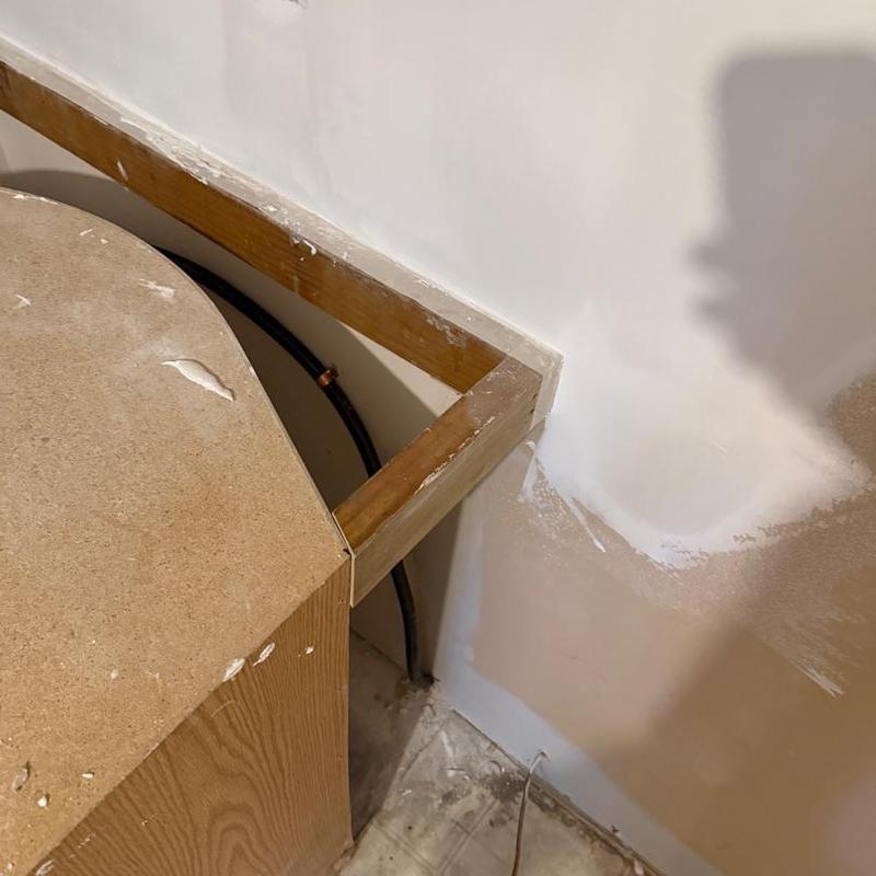 Gas and water lines behind wooden counter frame