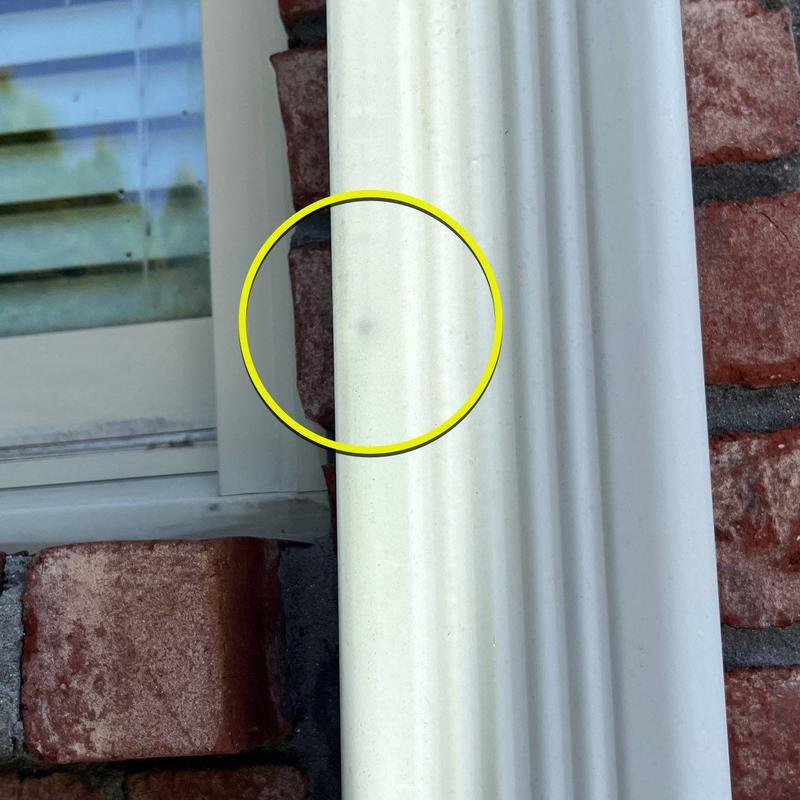 Vinyl siding hail damage circled near window trim