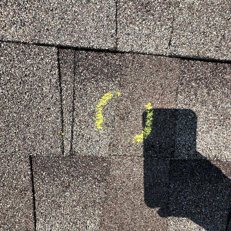 Asphalt roof shingle hail damage marked with yellow paint