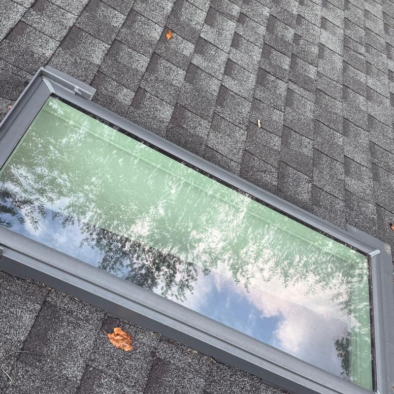 Skylight installation on shingle roof with reflections