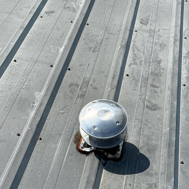 Metal roof vent with rust and hail damage marks