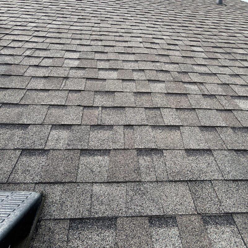 Asphalt shingles with visible hail damage on roof surface