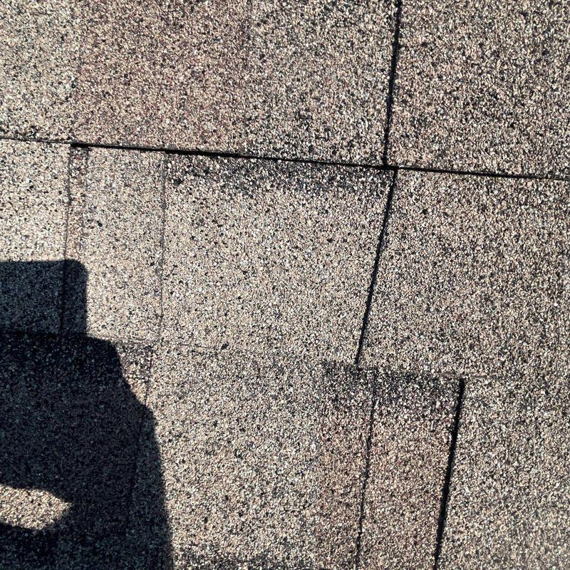 Asphalt roofing shingles with hail impact damage