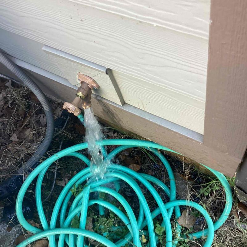 Outdoor faucet with water flowing into garden hose coils