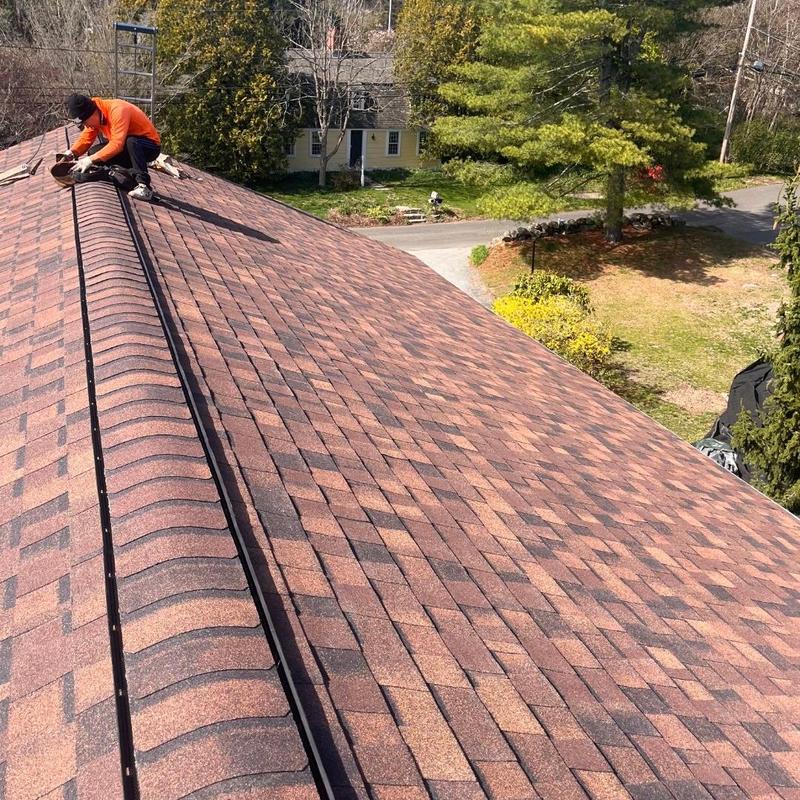 Asphalt shingle roof ridge cap installation on house