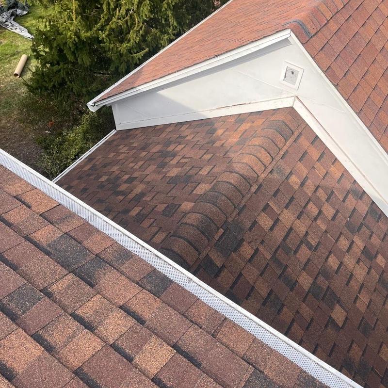 Asphalt shingle roof with ridge cap and gutter guards